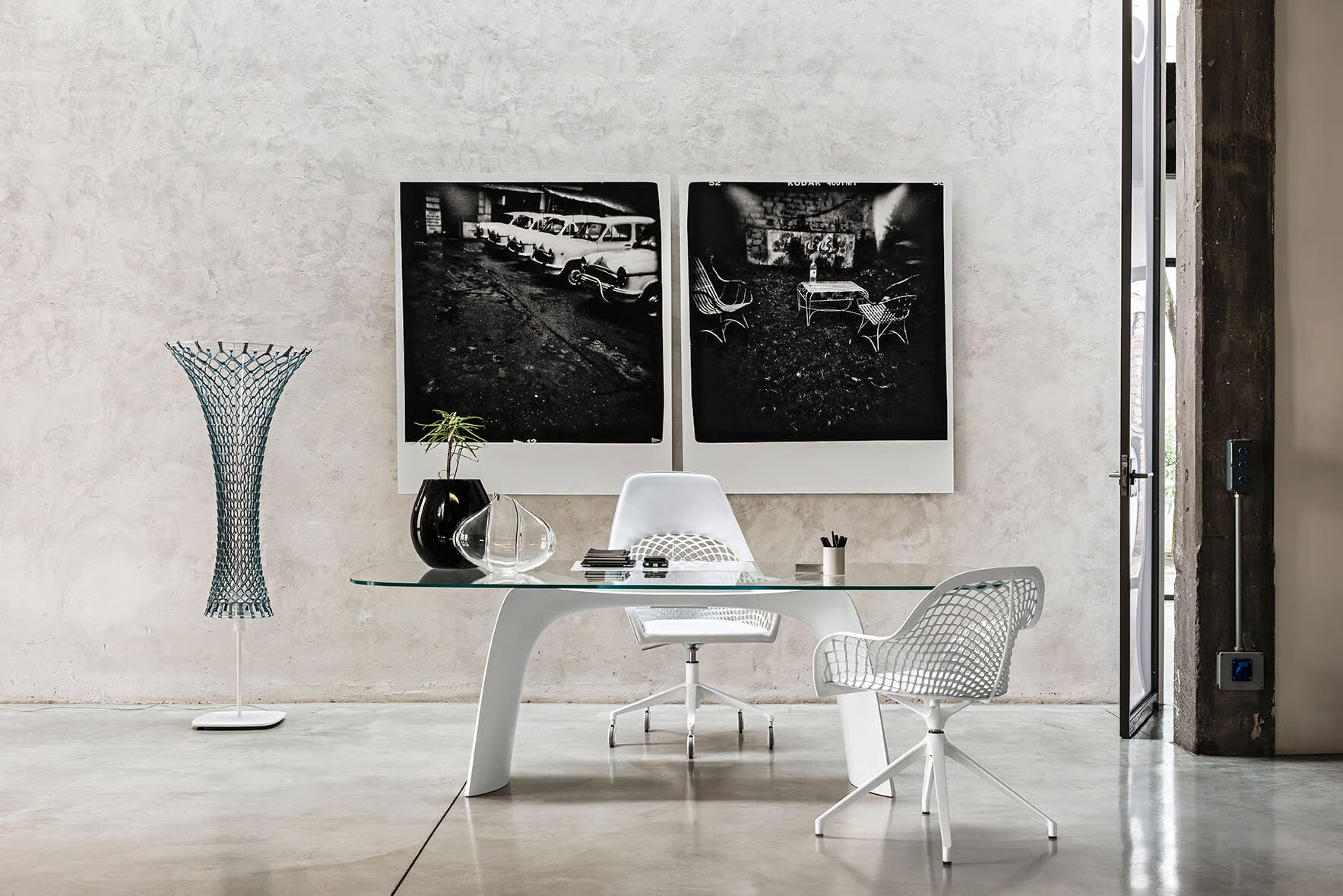 Modern office interior with a glass desk, chairs, and wall art.